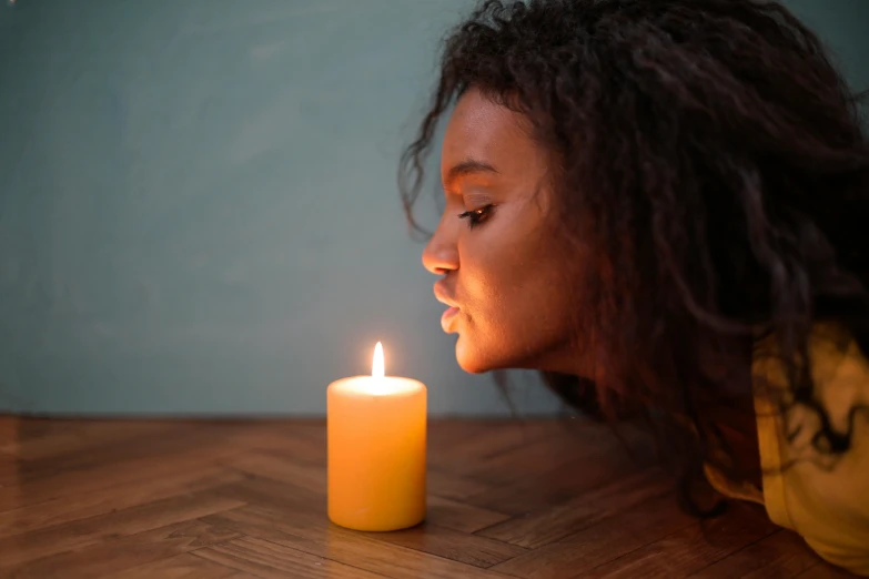 a woman blowing out a candle on a table, trending on pexels, yellow aura, black young woman, profile image, light stubble