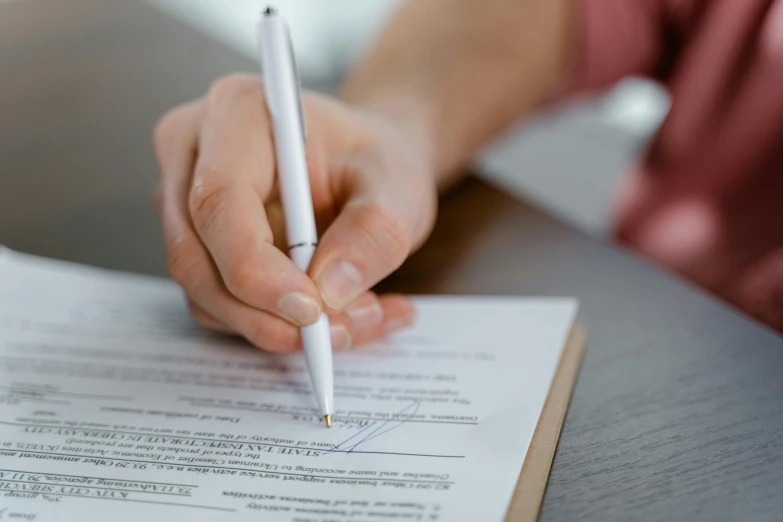 a person writing on a piece of paper with a pen, post appocalyptic, hand on table, forms, casey cooke