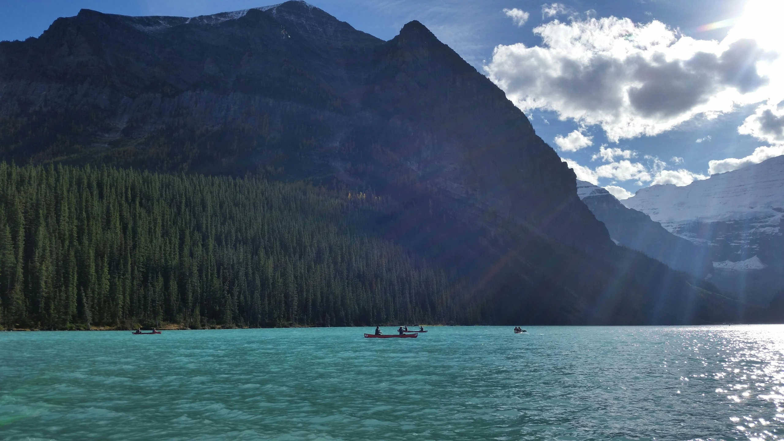 a large body of water with a mountain in the background, by Jessie Algie, pexels contest winner, hurufiyya, small canoes, banff national park, light blue water, sculls