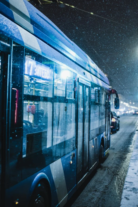 a bus parked on the side of the road in the snow, by Adam Marczyński, pexels contest winner, busy wet street at night, vibrant but dreary blue, square, thumbnail