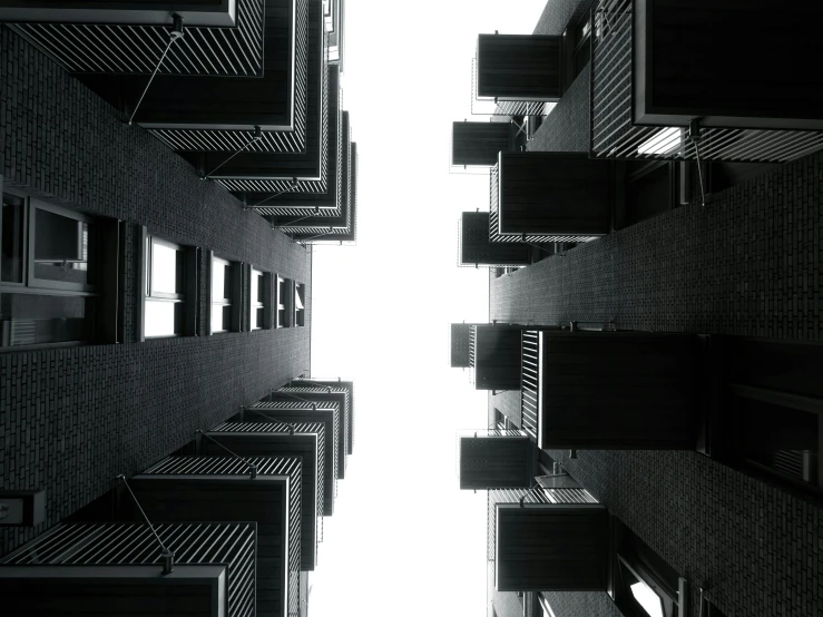a black and white photo of a tall building, by Jacob Toorenvliet, unsplash, brutalism, view from bottom to top, alleys, bottom view, high quality photo