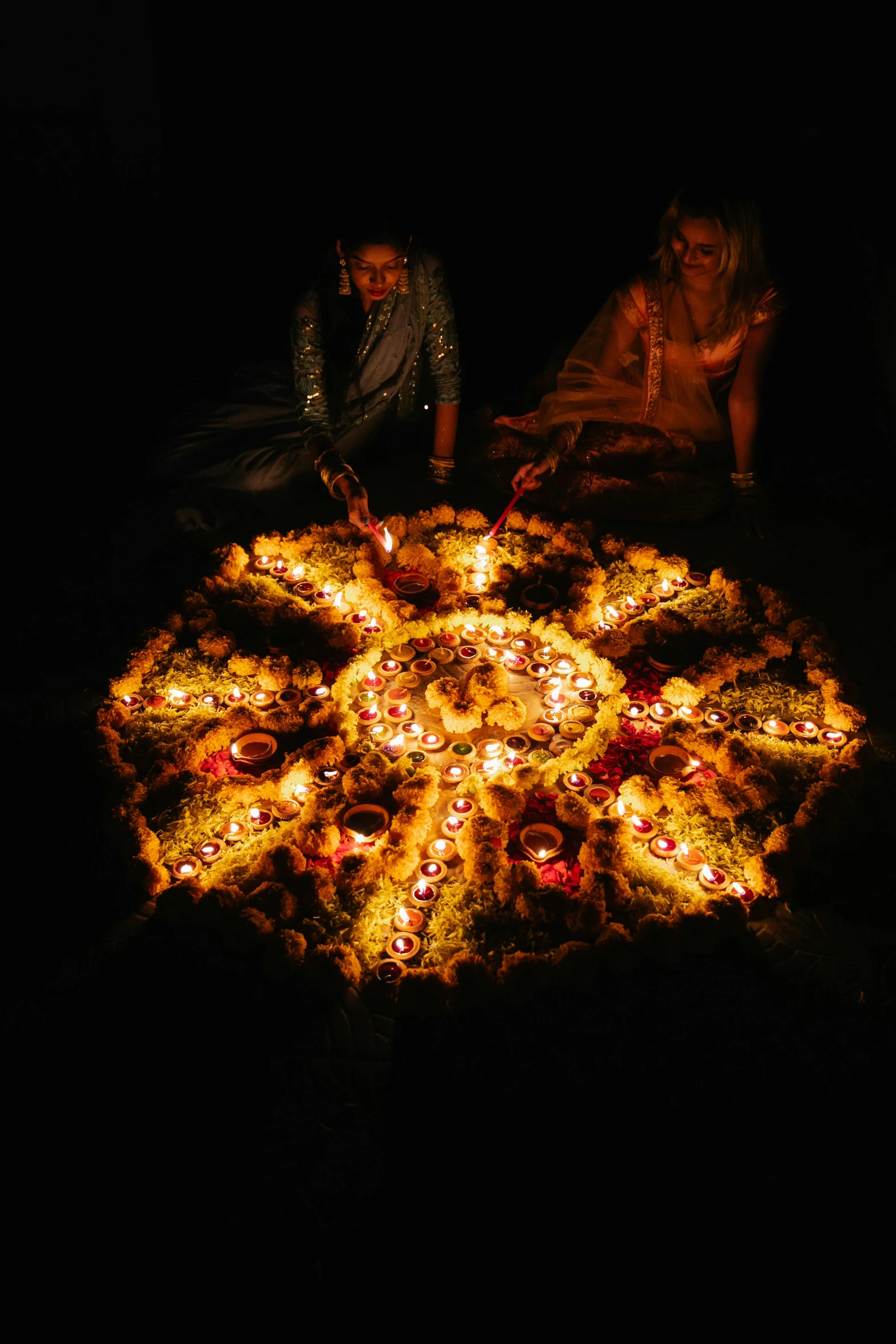 a group of people sitting around a large pizza, by Matt Stewart, land art, glowing imperial motifs, uttarakhand, lotuses, candles