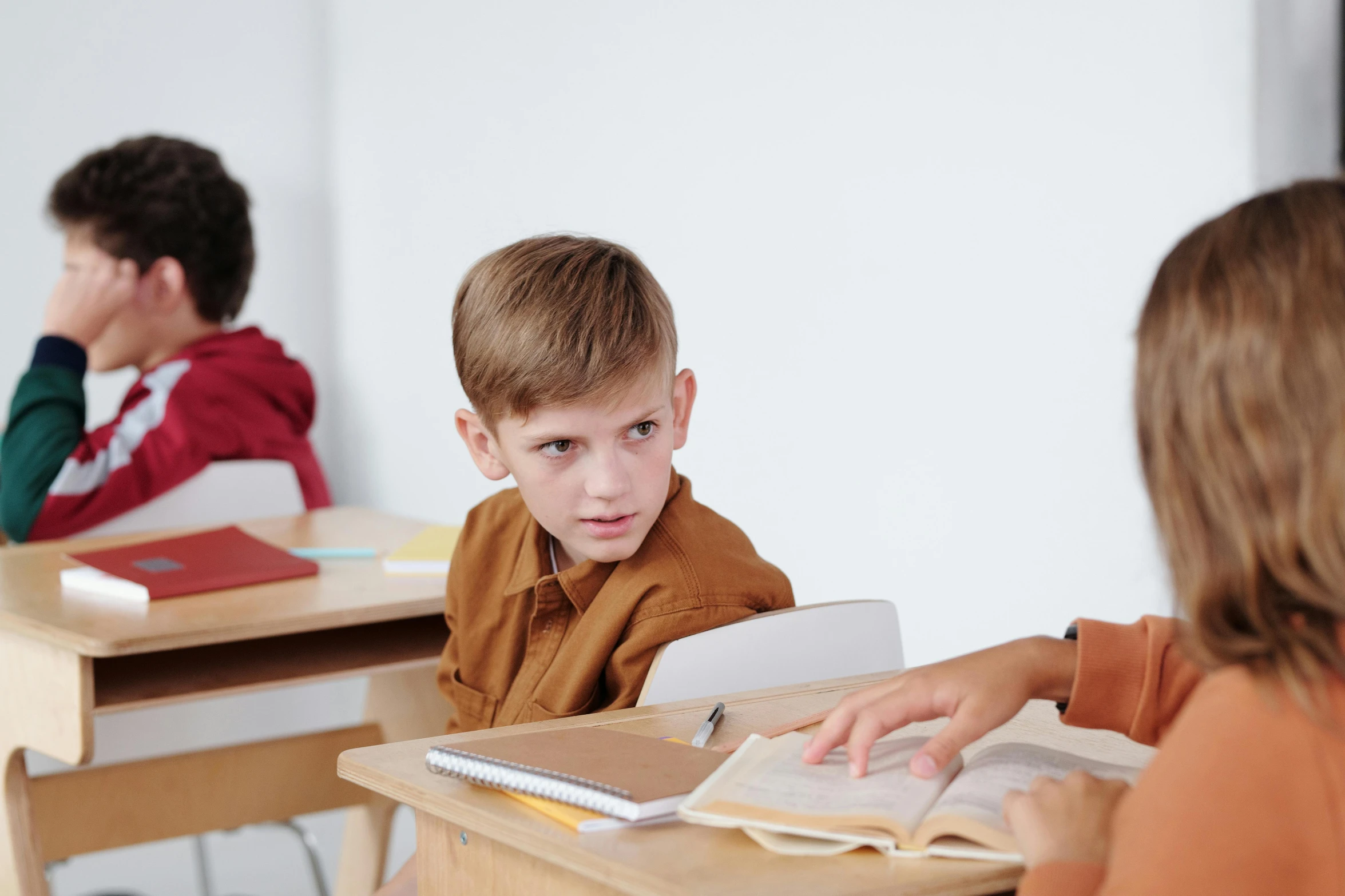 a group of children sitting at desks in a classroom, pexels contest winner, incoherents, angry look in his face, medium shot of two characters, 15081959 21121991 01012000 4k, boy with neutral face