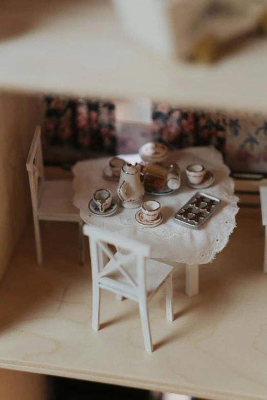 a doll house with a table and chairs, inspired by Annabel Kidston, unsplash, rococo, close up shot from the top, drinking tea, low quality photograph, model kit