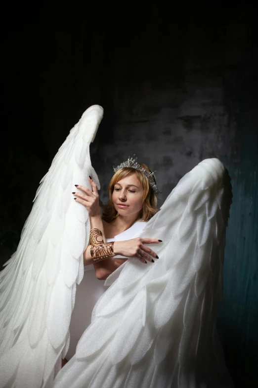 a woman in a white dress is holding an angel, pexels contest winner, with two pairs of wings, in a photo studio, tattooed, sydney sweeney