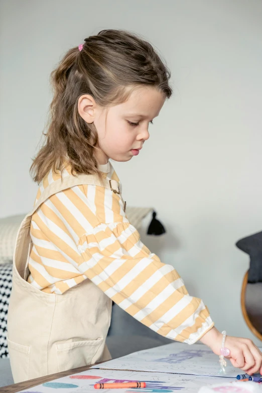 a little girl that is standing in front of a table, a picture