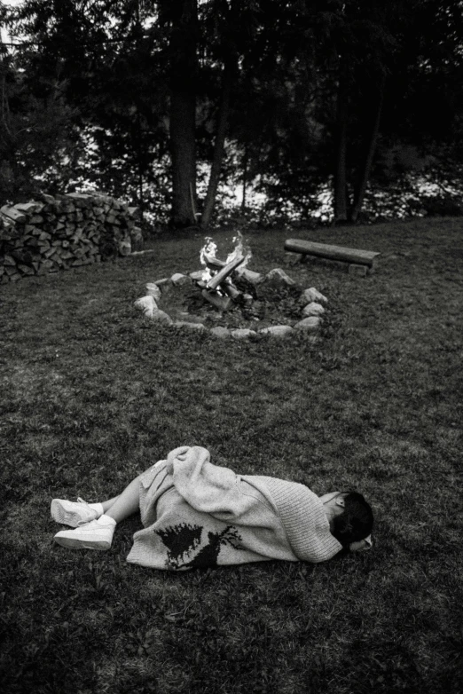 a black and white photo of a person laying in the grass, by Larry Fink, land art, campfire in background, ffffound, nishihara isao, summoning circle