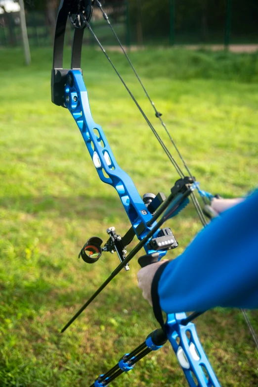 a close up of a person holding a bow and arrow, kobalt blue, blue metal, sports setting, outdoor