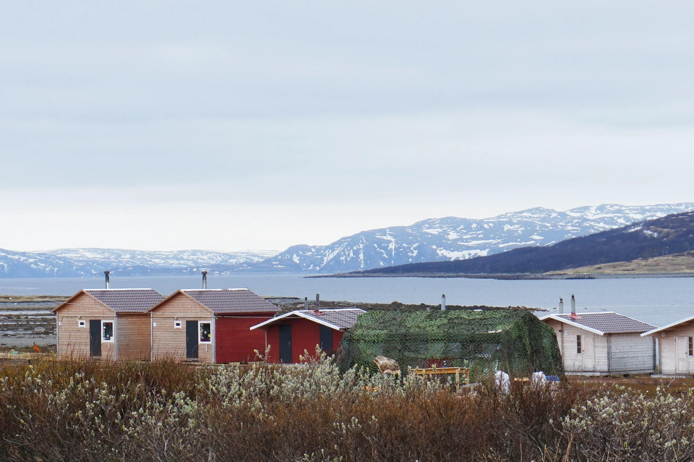 a number of houses near a body of water, by Louisa Matthíasdóttir, unsplash, hurufiyya, distant mountains, joel sternfeld, inuk, three - quarter view