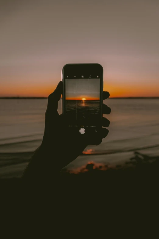 a person taking a picture of a sunset on a cell phone, a picture, by Robbie Trevino, unsplash contest winner, realism, looking into camera, minimalist photo, slightly pixelated, dark photo