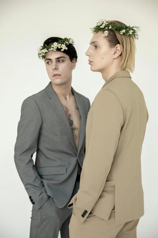 a man and a woman standing next to each other, by Nina Hamnett, non binary model, dressed in laurel wreath, tan suit, with flowers