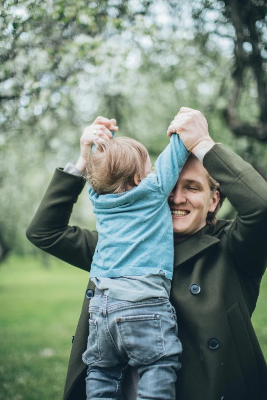 a man holding a small child in his arms, pexels contest winner, dancing with each other, springtime, a green, caspar david