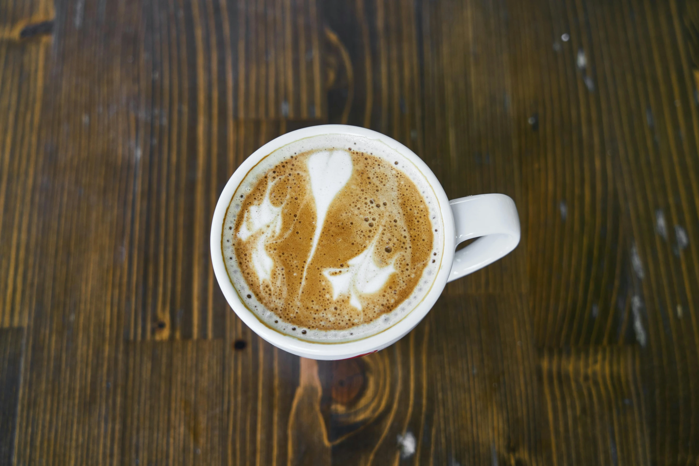 a cup of coffee sitting on top of a wooden table, by Carey Morris, pexels, milk, top angle view, profile image, thumbnail