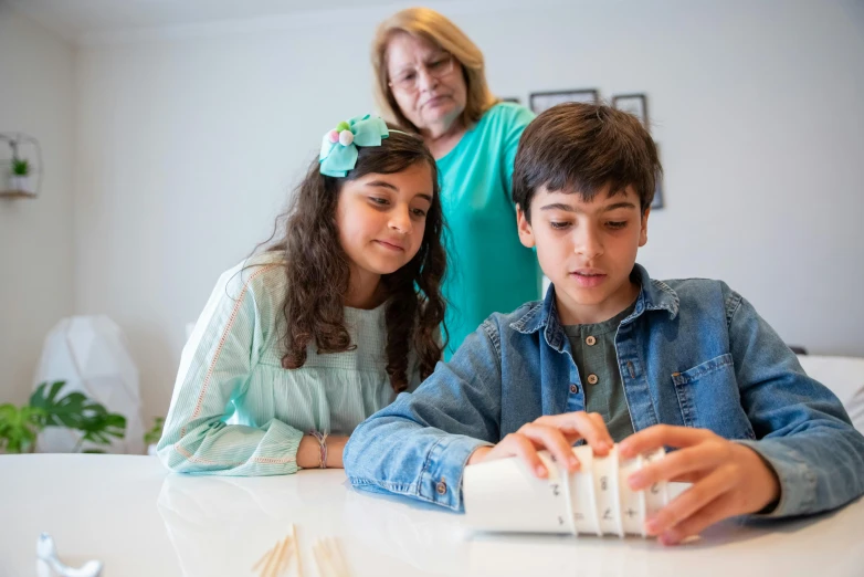 a couple of kids that are sitting at a table, pexels contest winner, interactive art, newton's cradle, slide show, teenage boy, person in foreground