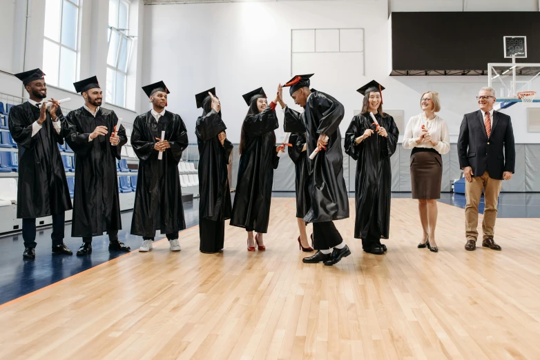 a group of people standing on top of a wooden floor, academic art, wearing an academic gown, high-quality photo, thumbnail, head down