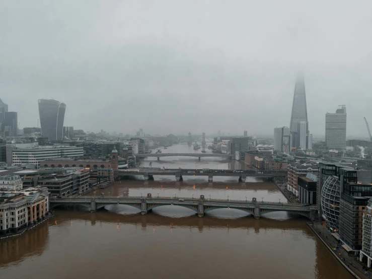 a river running through a city next to tall buildings, inspired by Thomas Struth, pexels contest winner, foggy heavy rain, london south bank, grey, panoramic view