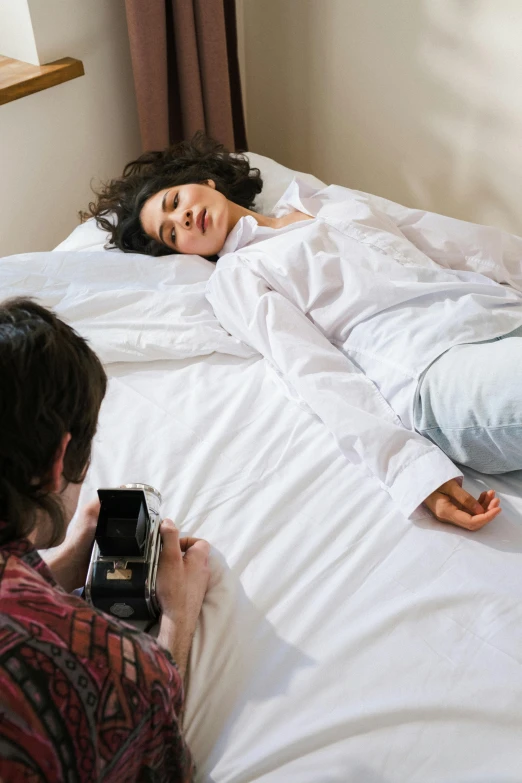 a man taking a picture of a woman laying in bed, inspired by Nan Goldin, visual art, wearing a light shirt, full body photoshoot, hyperrealistic movie filmstill, professional image