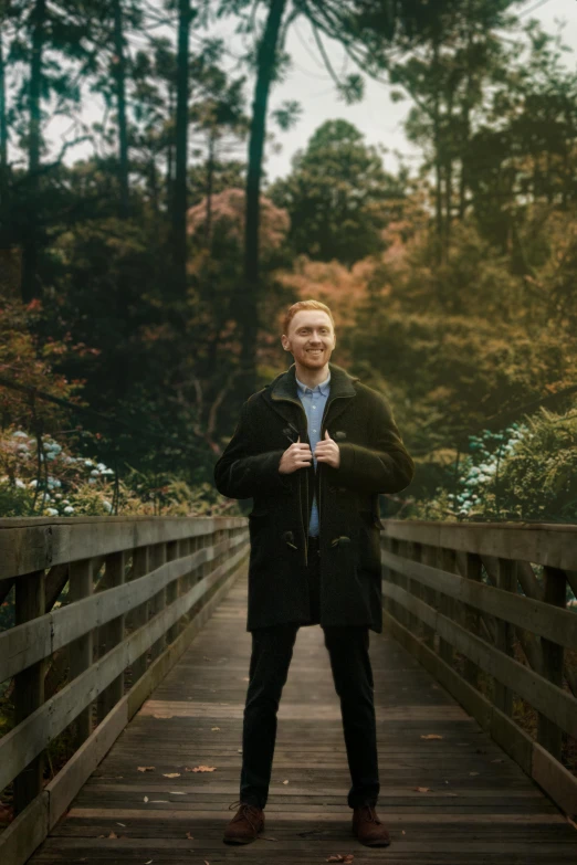 a man standing on top of a wooden bridge, an album cover, by Carey Morris, tom hiddleston, in tokio, in front of a forest background, hr ginger