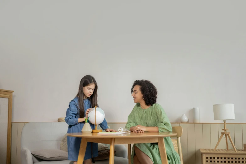 a woman and a little girl sitting at a table, pexels contest winner, interactive art, sphere, grey, neutral light, furniture