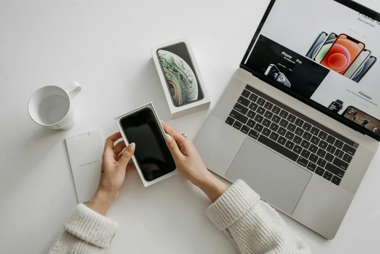 a person holding a smart phone in front of a laptop, a picture, trending on pexels, flatlay, sleek white, background image, professional product shot