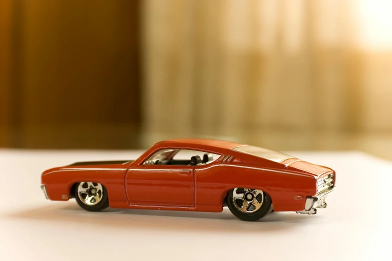 a red toy car sitting on top of a table, by Jay Hambidge, pexels contest winner, muscle cars, finely detailed car, rectangle, toy design