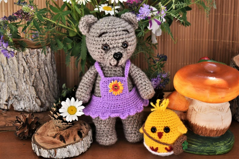 a crocheted teddy bear in a purple dress next to mushrooms and flowers, by Ivana Kobilca, pixabay contest winner, with chicks, mixture between an! owl and wolf, thumbnail, wooden