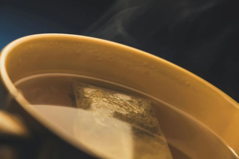 a cup of tea sitting on top of a table, smokey burnt envelopes, liquid gold, zoomed in, thumbnail