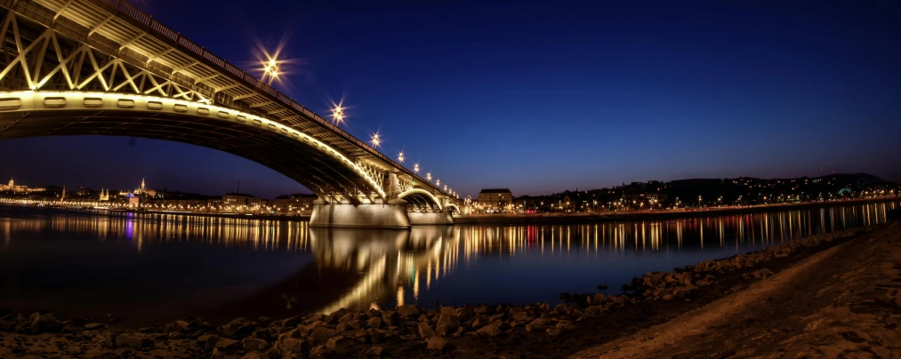 a bridge over a body of water at night, by Josef Navrátil, pexels contest winner, fan favorite, budapest, seville, 3 ds max + v - ray