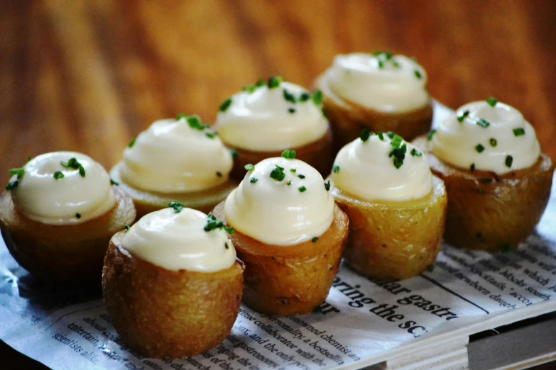 a bunch of cupcakes sitting on top of a newspaper, potato skin, bulbous, decadent, white