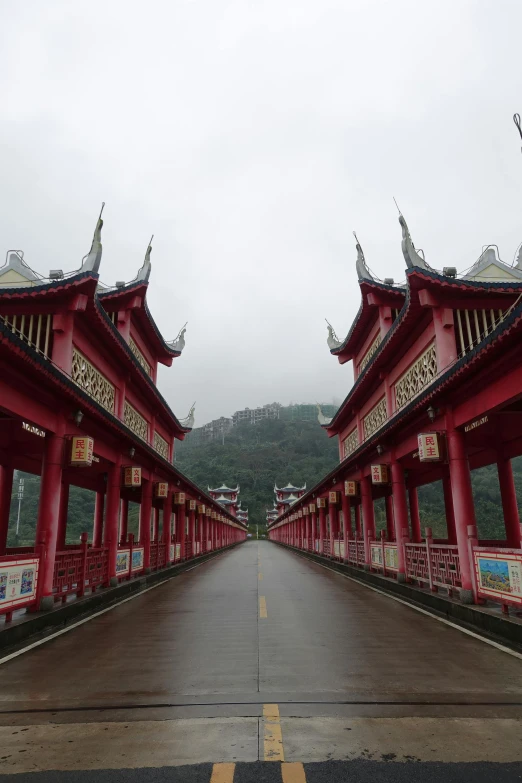 a couple of red buildings sitting on top of a road, inspired by Zhang Sengyao, mingei, massive arch, rainy, covered bridge, completely empty