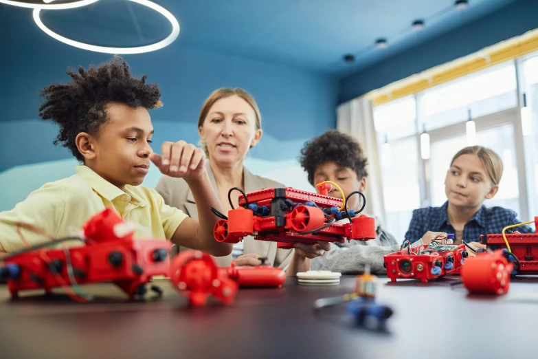 a group of children sitting around a table playing with legos, pexels contest winner, red and black robotic parts, avatar image, 40 years old women, argos