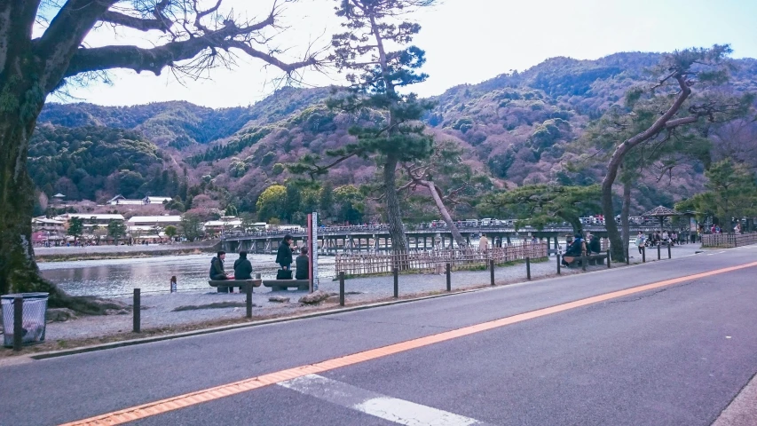a group of people standing on the side of a road, inspired by Sesshū Tōyō, unsplash, sōsaku hanga, river and trees and hills, iphone picture, town, けもの