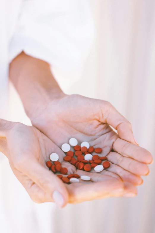 a person holding a handful of pills in their hands, a digital rendering, by Elsa Bleda, unsplash, antipodeans, white and red color scheme, instagram post, taken in the late 2010s, morning detail