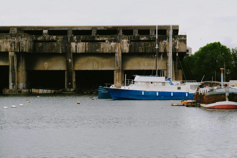 a couple of boats that are in the water, a portrait, unsplash, brutalism, sitting under bridge, picton blue, ignant, bulky build