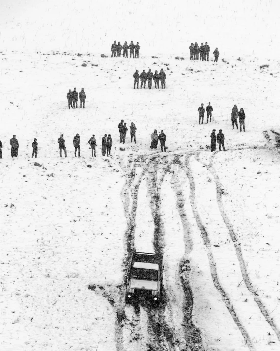 a group of people standing on top of a snow covered slope, inspired by Antanas Sutkus, jeep, photo of war, treacherous road, in the middle of a snow storm