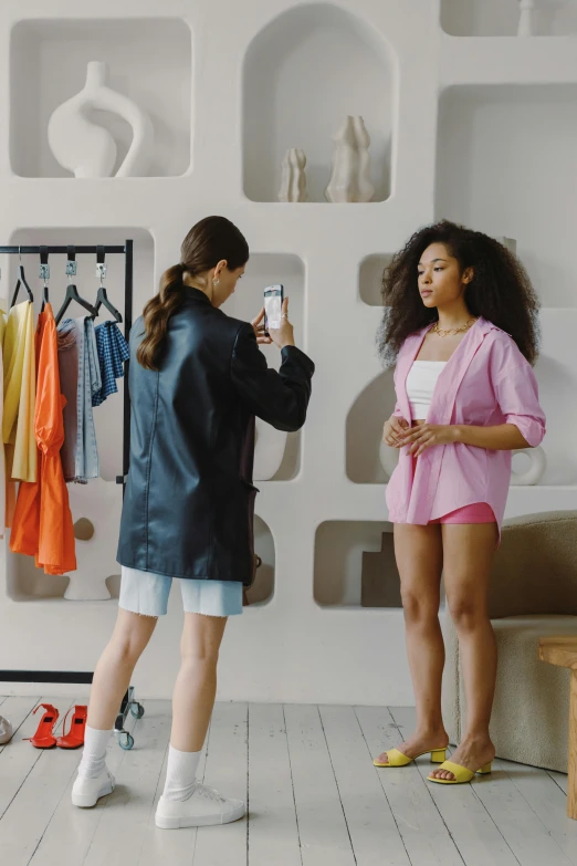 two women standing next to each other in a room, trending on pexels, happening, wearing shorts, goddess checking her phone, wearing a fancy jacket, ecommerce photograph