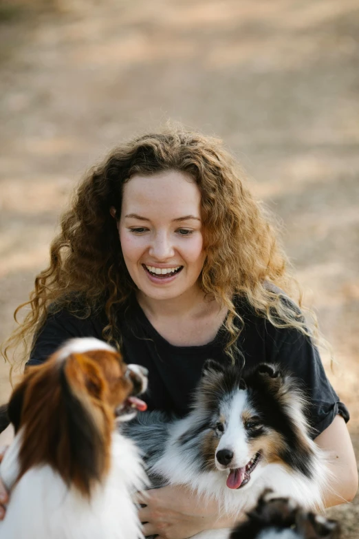 a woman sitting on the ground with two dogs, pexels contest winner, curly haired, smiling young woman, profile image, aussie