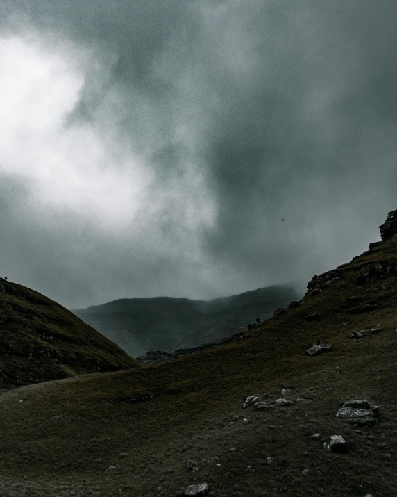 a person standing on top of a hill under a cloudy sky, by Muggur, pexels contest winner, les nabis, ominous dark background, in a valley, trending photo, overcast gray skies