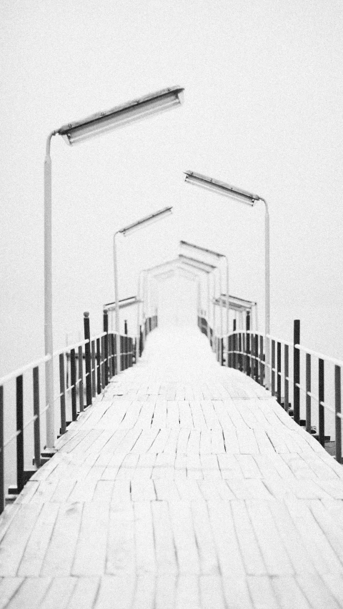 a black and white photo of a pier, conceptual art, ffffound, snowing, overexposed photograph, white colors