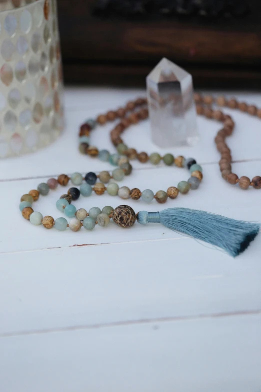 a close up of a beaded necklace with a tassel, unsplash, on wood, figure meditating close shot, cyan mist, full front view