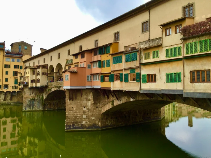 a bridge over a body of water with buildings in the background, a photo, inspired by Michelangelo Buonarotti, pexels contest winner, renaissance, square, colorful caparisons, florentine school, a green