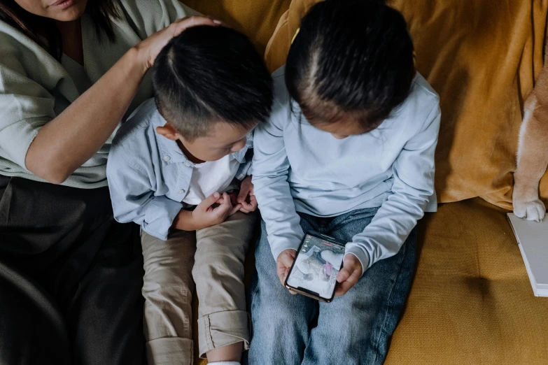 a woman and two children sitting on a couch, a picture, trending on pexels, mobile game style, cell phones, denim, ruan jia and brom