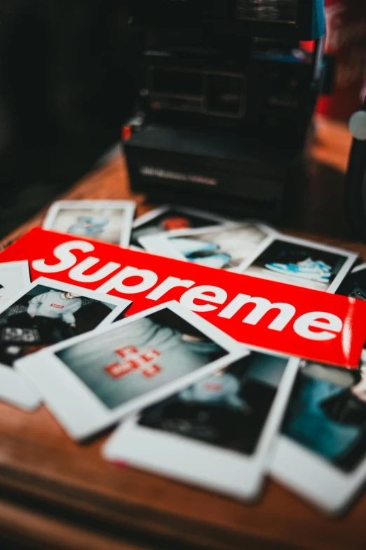 a pile of photos sitting on top of a wooden table, a polaroid photo, trending on pexels, suprematism, trending on r/streetwear, supreme, surgeon, sticker