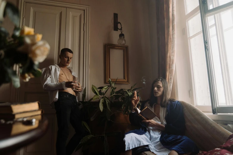 a man standing next to a woman sitting on a couch, a portrait, inspired by Balthus, pexels contest winner, renaissance, alessio albi, costumes from peaky blinders, medium format. soft light, album cover