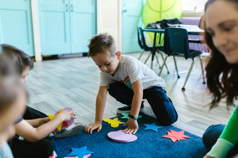 a group of children sitting on the floor playing with paper plates, by Arabella Rankin, pexels contest winner, sitting in the classroom, hugging his knees, te pae, tessellating patterns