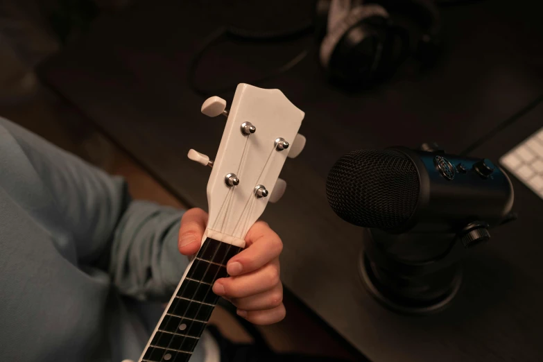 a person holding a guitar in front of a microphone, alexa mini, white finish, detailed product image, eye level view