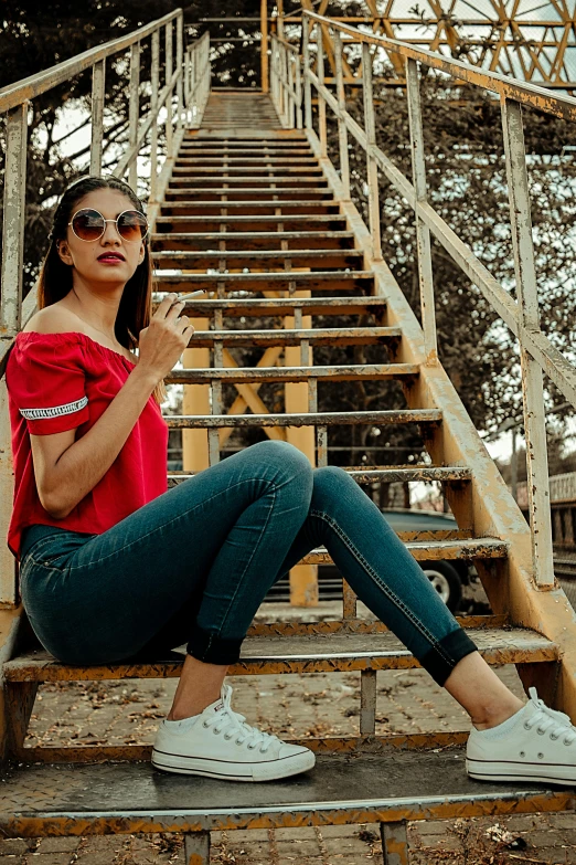 a woman sitting on a set of stairs, pexels contest winner, red shirt, wearing cool sunglasses, wearing jeans, trending on artstion