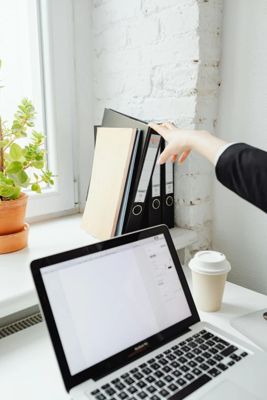a woman pointing at a laptop computer on a desk, pexels contest winner, private press, shelf, clean and organized, profile image, no - text no - logo