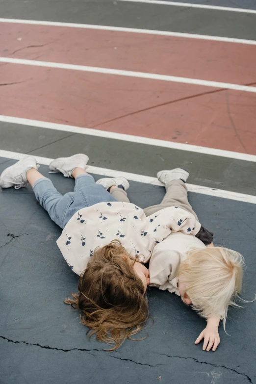 a couple of kids laying on top of a tennis court, by Nina Hamnett, pexels contest winner, bedhead, facing away, twins, katey truhn