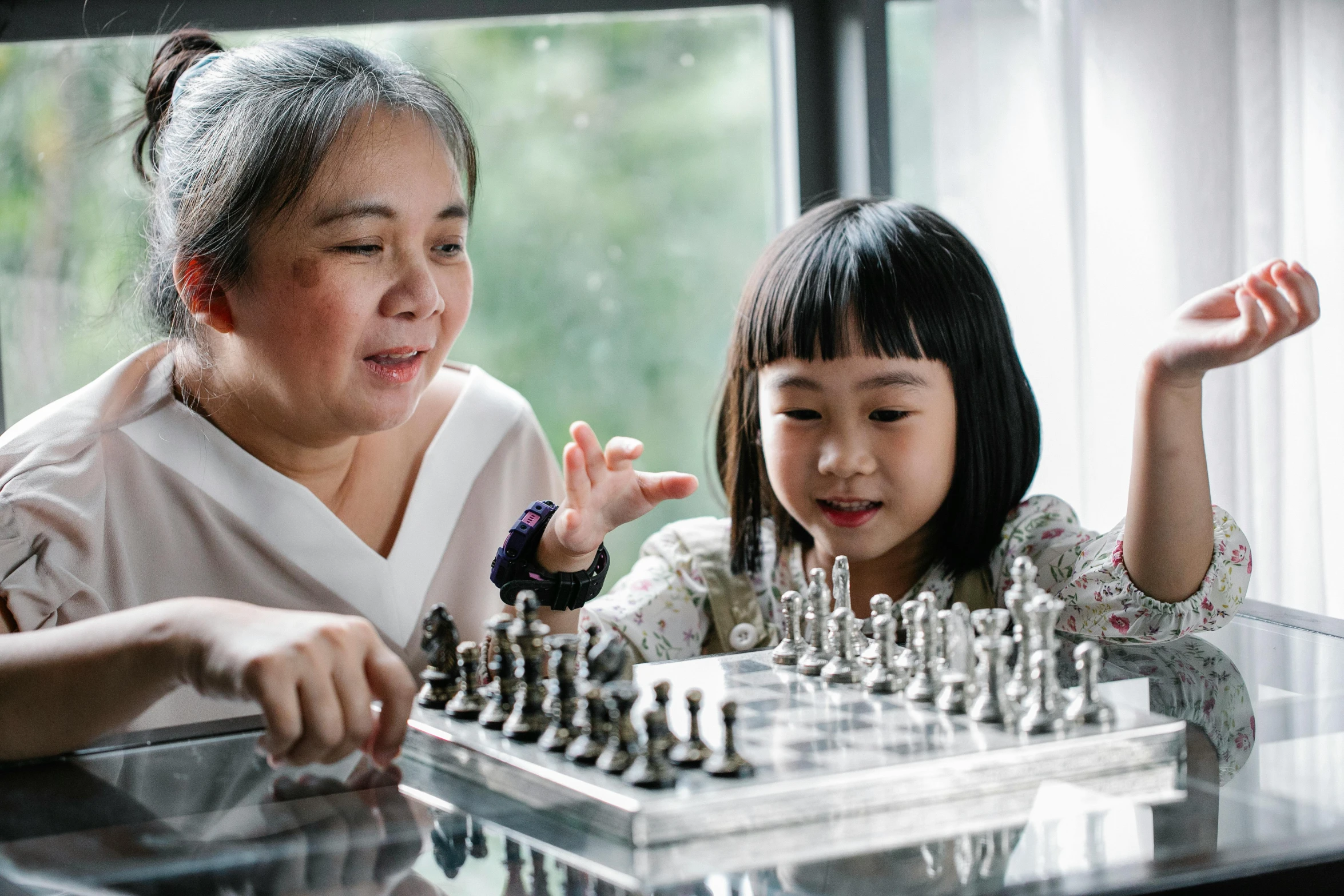 a woman and a little girl playing a game of chess, pexels contest winner, interactive art, zeen chin and terada katsuya, caretaker, profile image, still photograph